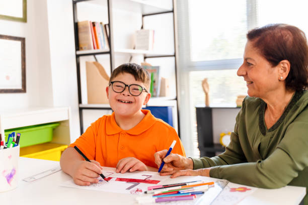 A boy with down syndrome is in a classroom with his teacher
